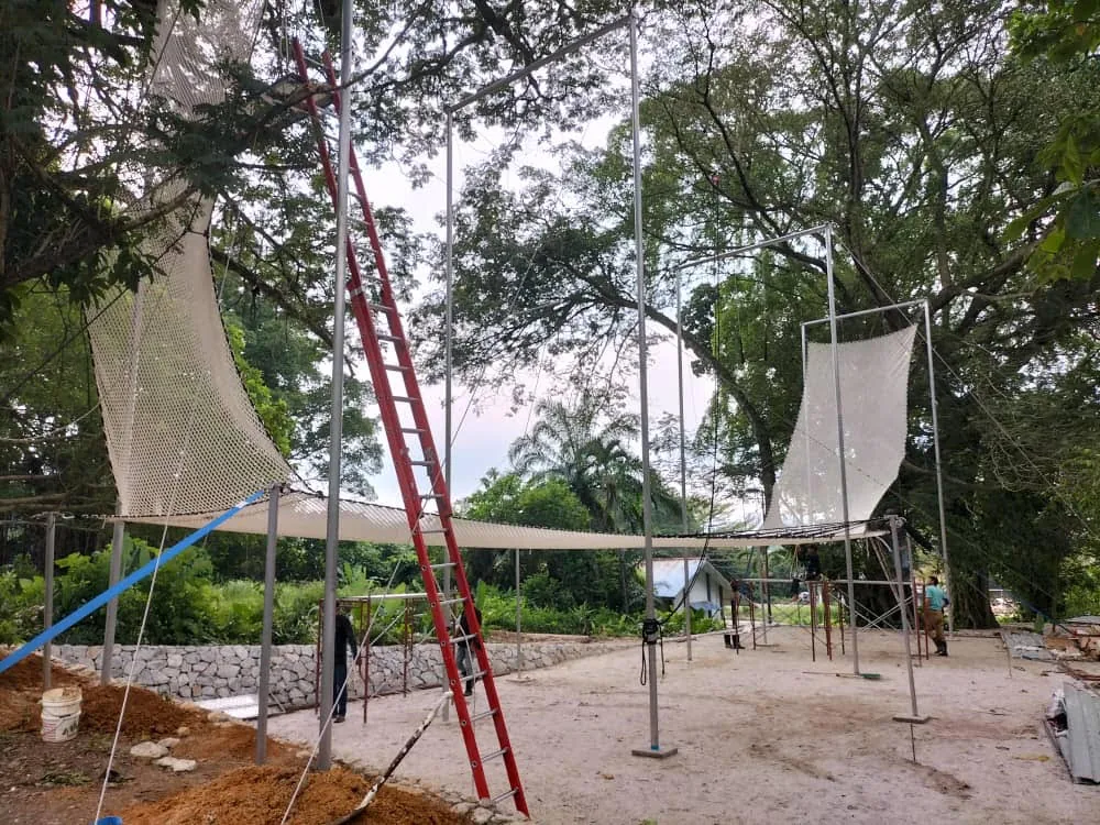 Full-size flying trapeze rig installed among mature trees — Escape theme park, Malaysia — MACA flying trapeze rig