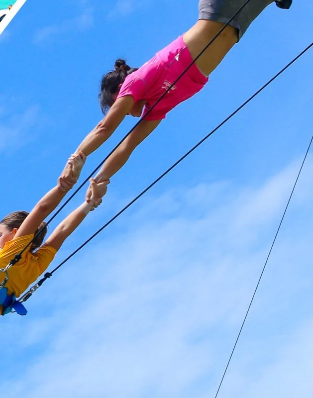 Catcher and flyer mid-catch on a flying trapeze rig — MACA flying trapeze rig